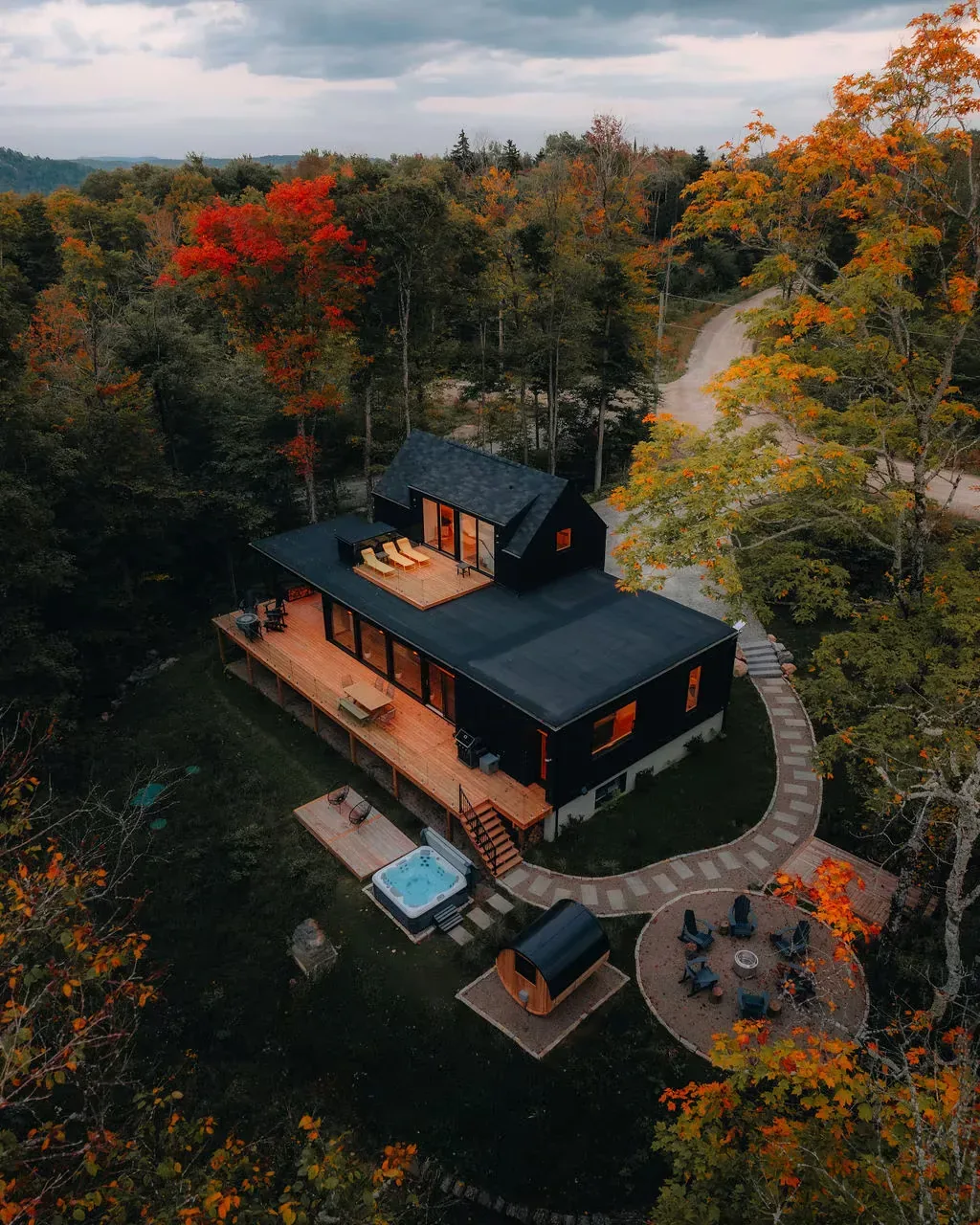 Aerial view of a property at dusk with a hot tub, sauna and firepit in the garden